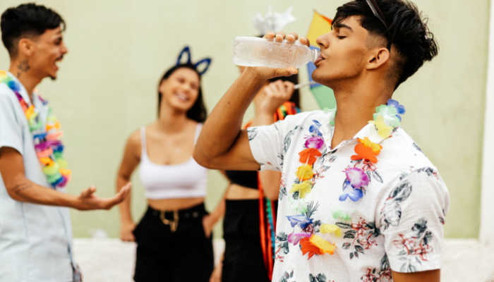 homem fantasiado bebendo água se hidratando durante bloco de carnaval de rua 